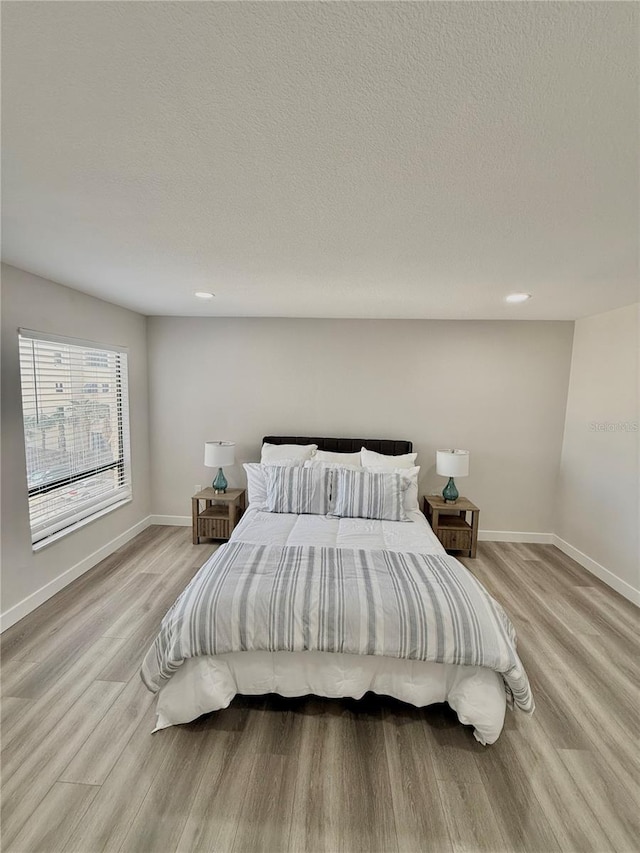 bedroom with a textured ceiling and light wood-type flooring