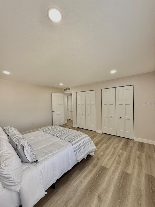 bedroom featuring two closets and light hardwood / wood-style flooring