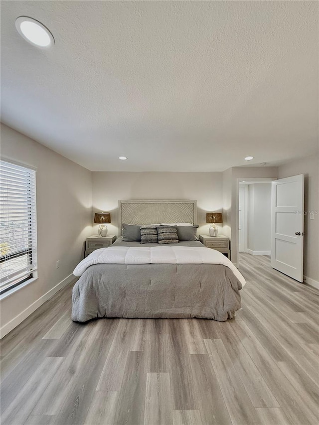 bedroom featuring a textured ceiling and light hardwood / wood-style flooring