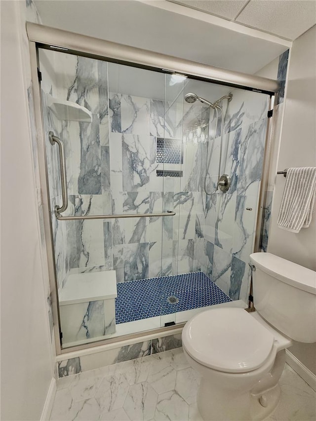 bathroom featuring a shower with door and toilet