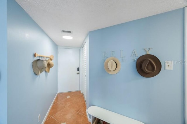 corridor with light tile patterned floors and a textured ceiling