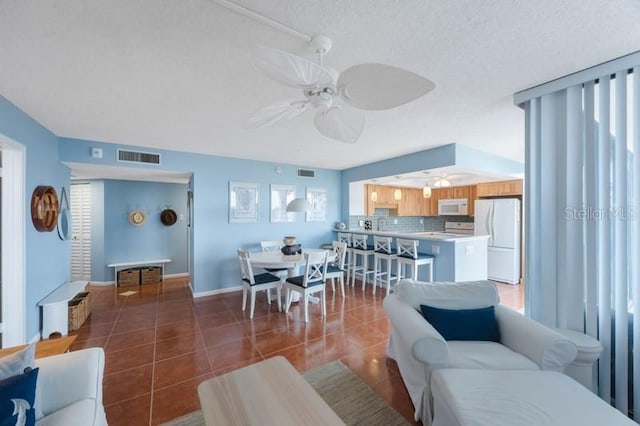 living room with ceiling fan, a textured ceiling, and dark tile patterned floors