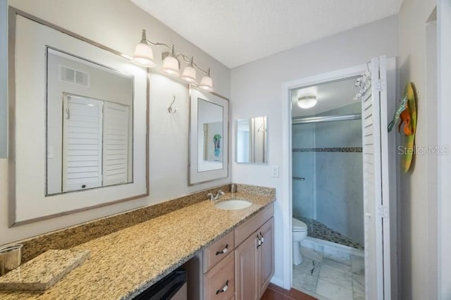 bathroom with toilet, vanity, a textured ceiling, and walk in shower