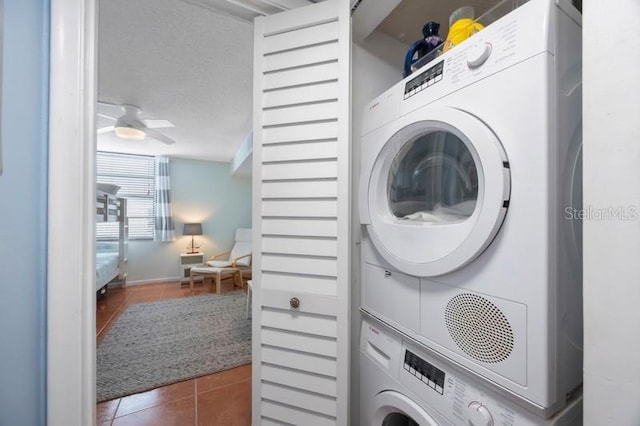 clothes washing area featuring stacked washer / drying machine, a textured ceiling, dark tile patterned floors, and ceiling fan