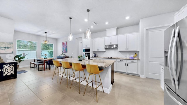 kitchen featuring white cabinets, backsplash, hanging light fixtures, stainless steel refrigerator with ice dispenser, and a center island with sink