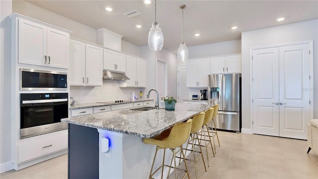 kitchen featuring stainless steel appliances, sink, a center island with sink, and white cabinets