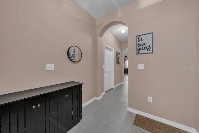 hall featuring light tile patterned flooring and a textured ceiling