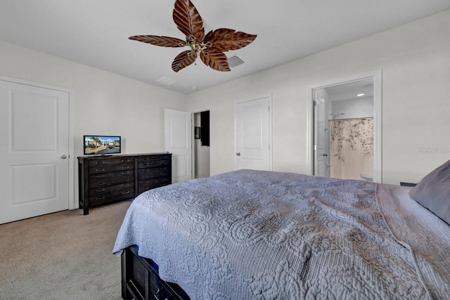 bedroom with ceiling fan, ensuite bath, and light colored carpet