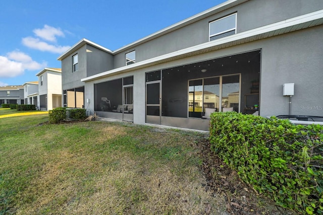 rear view of property with a lawn and a sunroom