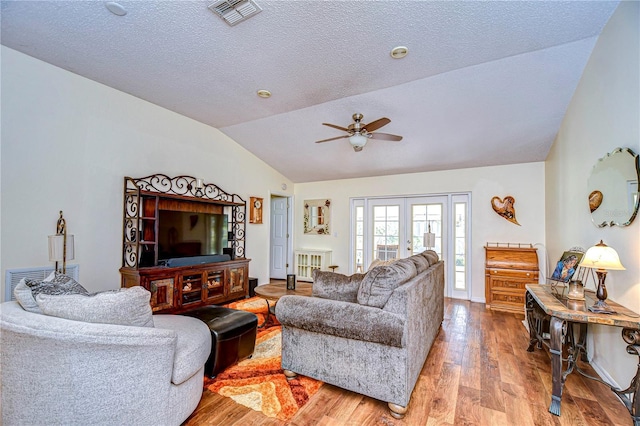 living room with hardwood / wood-style flooring, ceiling fan, a textured ceiling, vaulted ceiling, and french doors