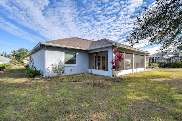 back of property featuring a sunroom and a lawn