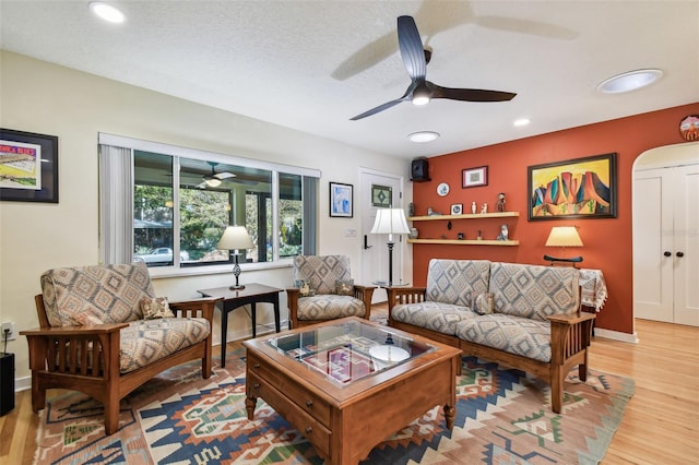 living room featuring ceiling fan, a textured ceiling, and light wood-type flooring