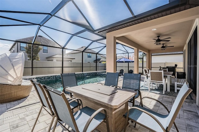 view of patio / terrace with a fenced in pool, pool water feature, ceiling fan, and glass enclosure