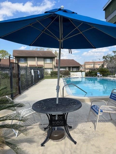 pool with a patio area and fence