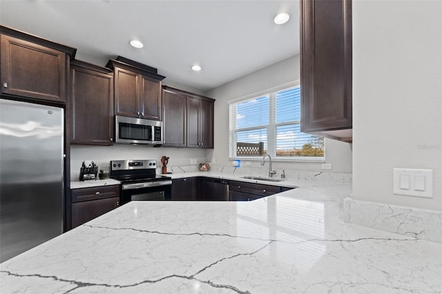 kitchen with stainless steel appliances, sink, dark brown cabinetry, and light stone counters