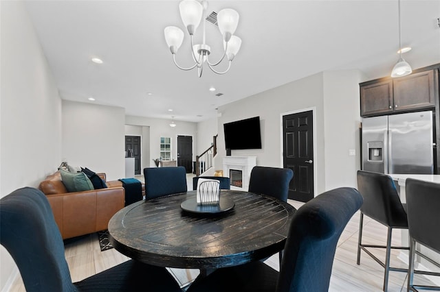 dining area with a premium fireplace, a chandelier, and light hardwood / wood-style floors