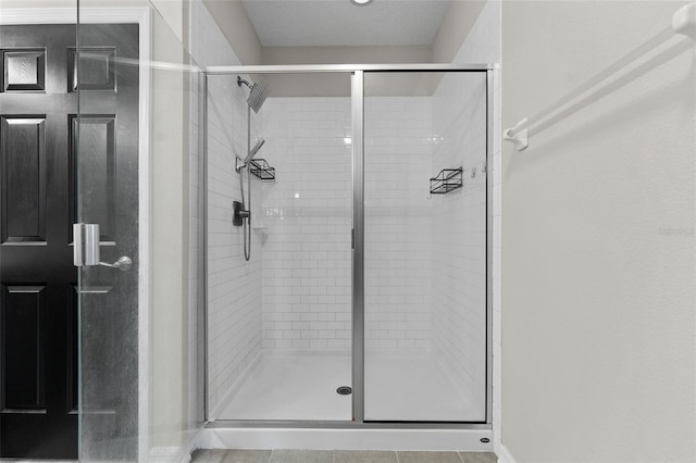 bathroom with tile patterned flooring and a shower with shower door