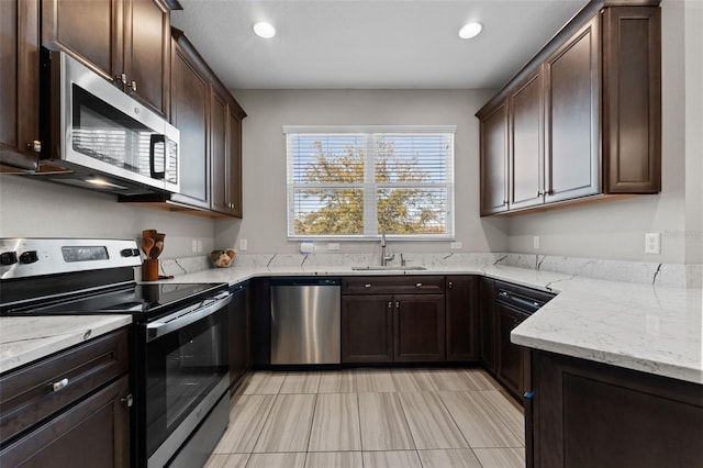 29913 Southwell Ln, Wesley Chapel, FL 33543 - kitchen with stainless steel appliances, a sink, dark brown cabinetry, light stone counters, and recessed lighting