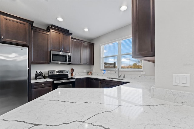 29913 Southwell Ln, Wesley Chapel, FL 33543 - kitchen with stainless steel appliances, a sink, light stone countertops, dark brown cabinets, and recessed lighting