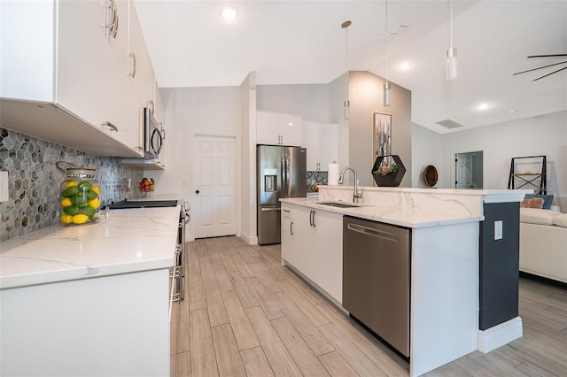 kitchen with sink, hanging light fixtures, stainless steel appliances, a kitchen island with sink, and white cabinets