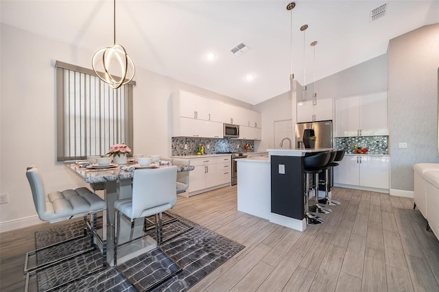 kitchen featuring white cabinetry, pendant lighting, vaulted ceiling, and a breakfast bar