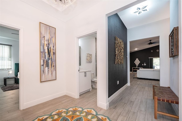 hallway with lofted ceiling, light hardwood / wood-style flooring, and a healthy amount of sunlight