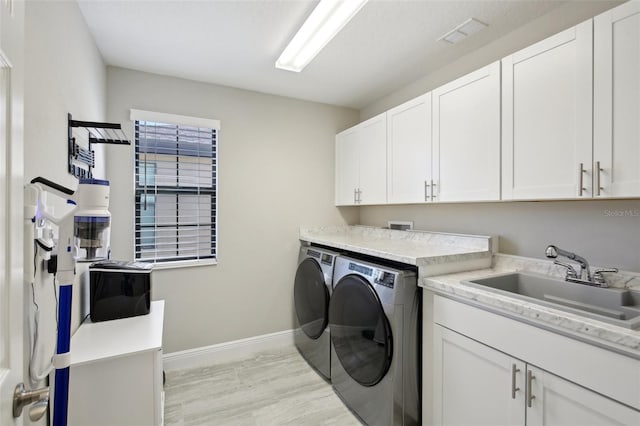 laundry room with a sink, visible vents, baseboards, cabinet space, and washing machine and clothes dryer