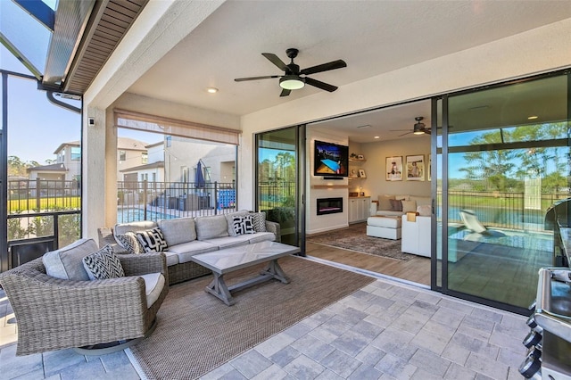 view of patio / terrace with an outdoor hangout area, glass enclosure, fence, and a ceiling fan