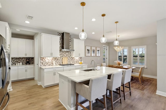 kitchen featuring a sink, backsplash, appliances with stainless steel finishes, and wall chimney range hood