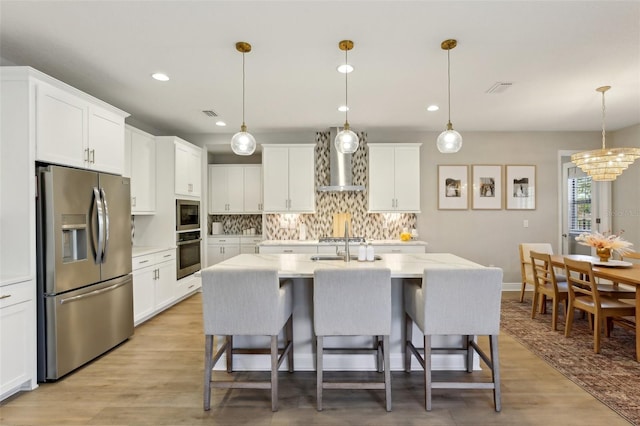 kitchen featuring visible vents, wall chimney exhaust hood, stainless steel appliances, white cabinetry, and backsplash