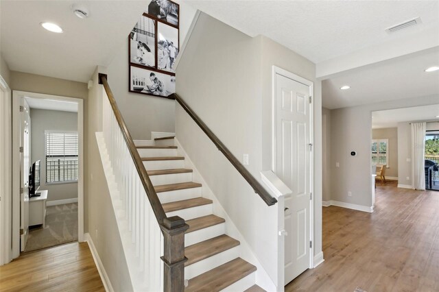 stairway with baseboards, visible vents, wood finished floors, and recessed lighting