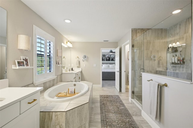 bathroom featuring a garden tub, a sink, two vanities, a ceiling fan, and a stall shower