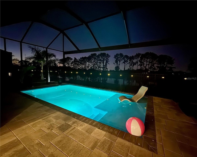 pool at twilight featuring a water slide, a patio area, and a lanai