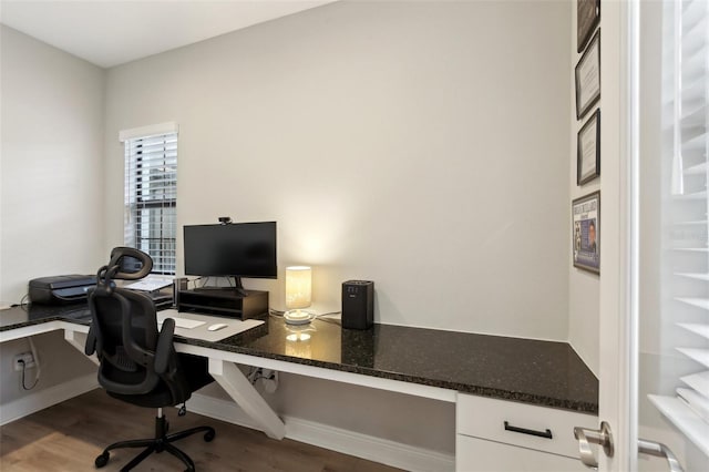 home office featuring baseboards, built in desk, and wood finished floors