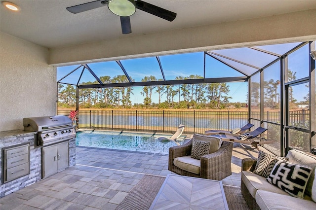 view of patio / terrace with an outdoor kitchen, glass enclosure, a water view, a grill, and fence