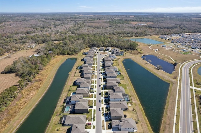 drone / aerial view featuring a water view, a wooded view, and a residential view