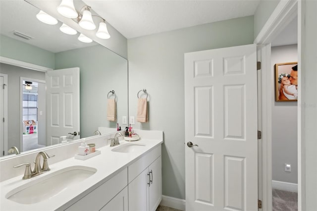 full bathroom featuring double vanity, baseboards, visible vents, and a sink