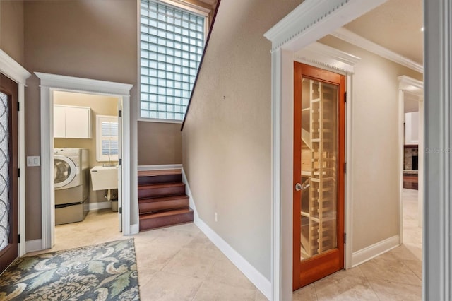 entryway with light tile patterned flooring, crown molding, and washer / clothes dryer