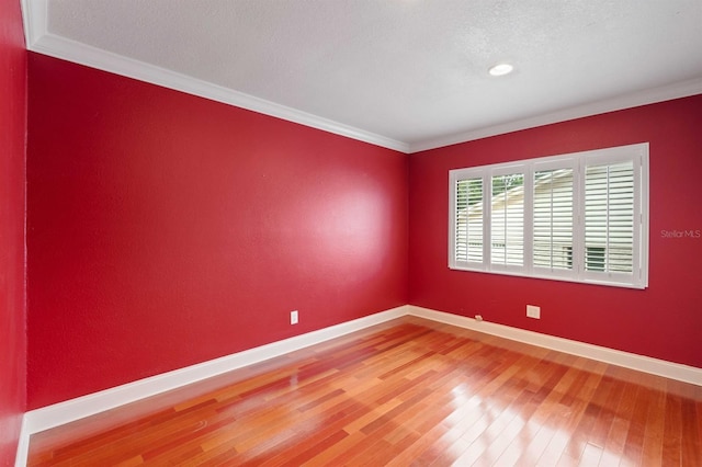 spare room featuring hardwood / wood-style flooring, a textured ceiling, and crown molding