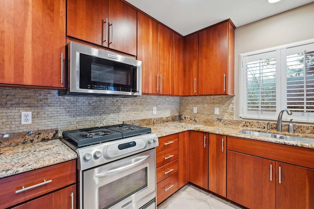 kitchen featuring sink, backsplash, light stone counters, and appliances with stainless steel finishes