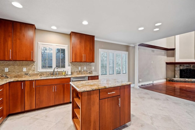 kitchen with sink, a large fireplace, backsplash, ornamental molding, and light stone counters