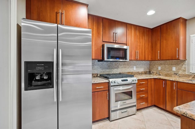 kitchen featuring light tile patterned flooring, decorative backsplash, light stone countertops, and appliances with stainless steel finishes