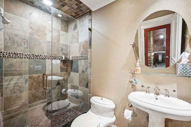 bathroom with sink, a shower with door, toilet, and crown molding