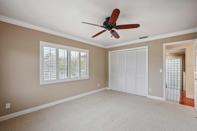 unfurnished bedroom with ceiling fan, a closet, ornamental molding, and light carpet