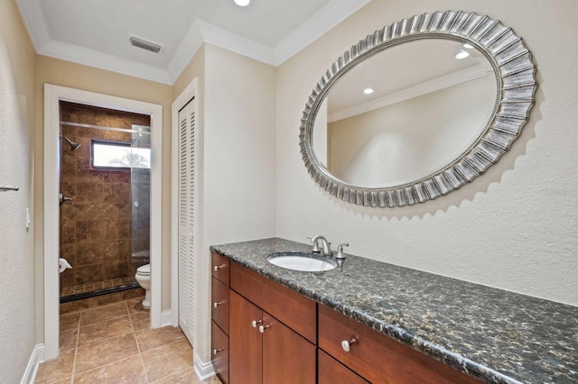 bathroom featuring tiled shower, toilet, ornamental molding, and vanity