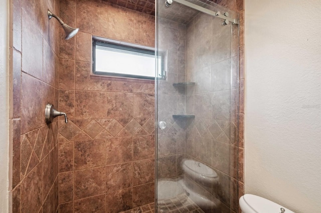 bathroom featuring toilet and a tile shower