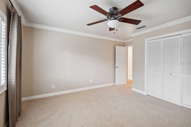 unfurnished bedroom featuring a closet, ceiling fan, crown molding, and light carpet