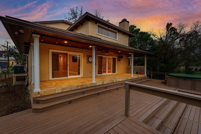 deck at dusk featuring cooling unit and a hot tub