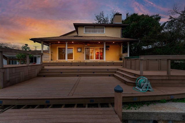 back house at dusk featuring a deck