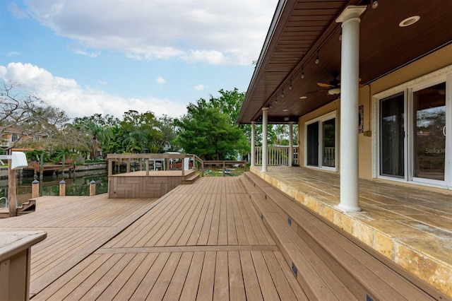 wooden deck with ceiling fan and a water view